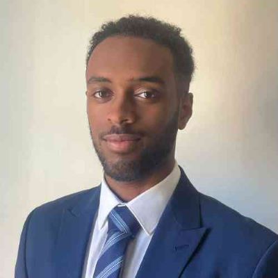 Portrait photo of Queen Mary graduate Rodas Wendemu. Rodas is smartly dressed, wearing a navy blue suit with blue tie.