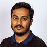 Shyikh Mahdi wearing a navy jumper and looking into the camera and smiling.